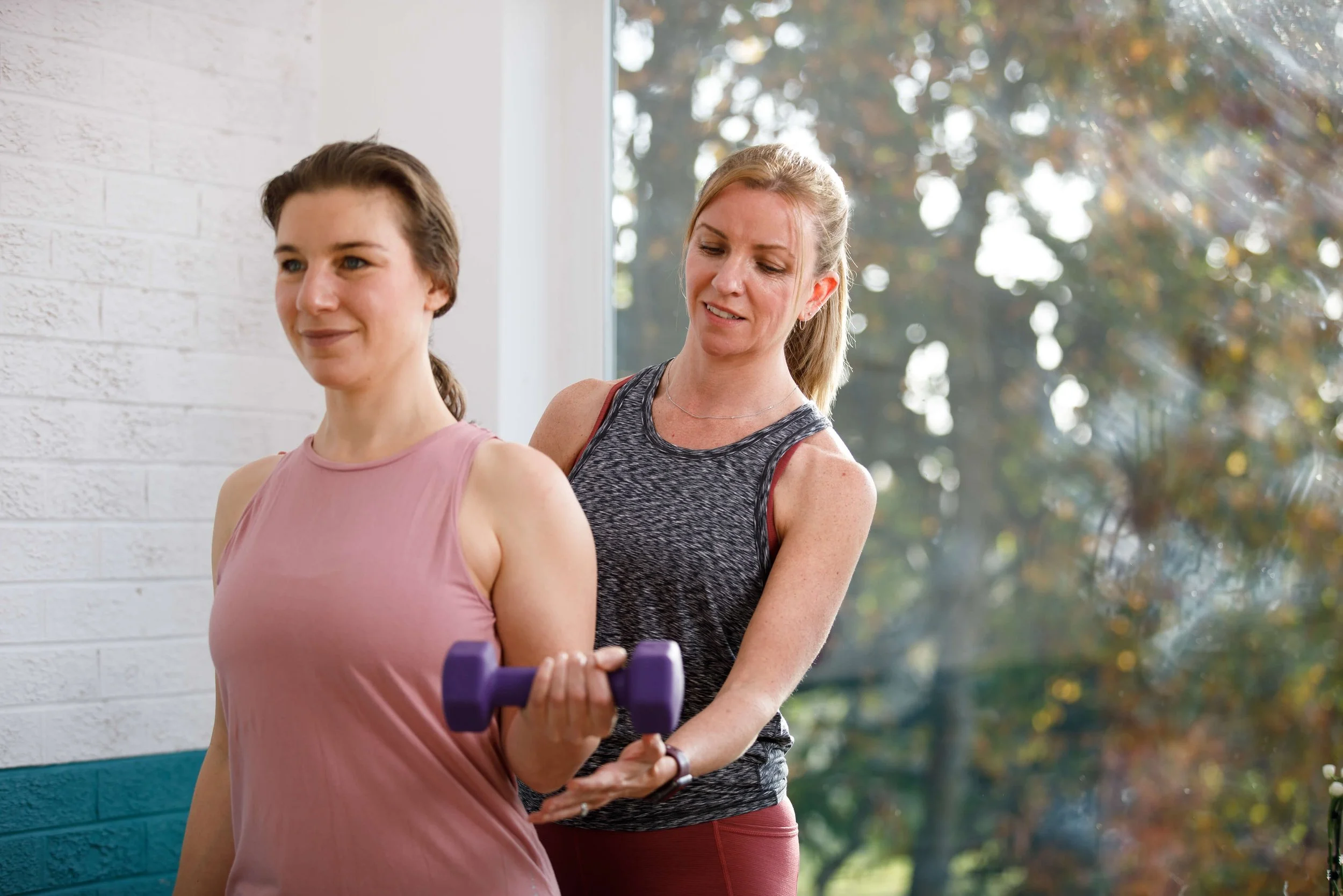 Louisa, founder at Move Well Studio helps a female student with posture during a private pilates session