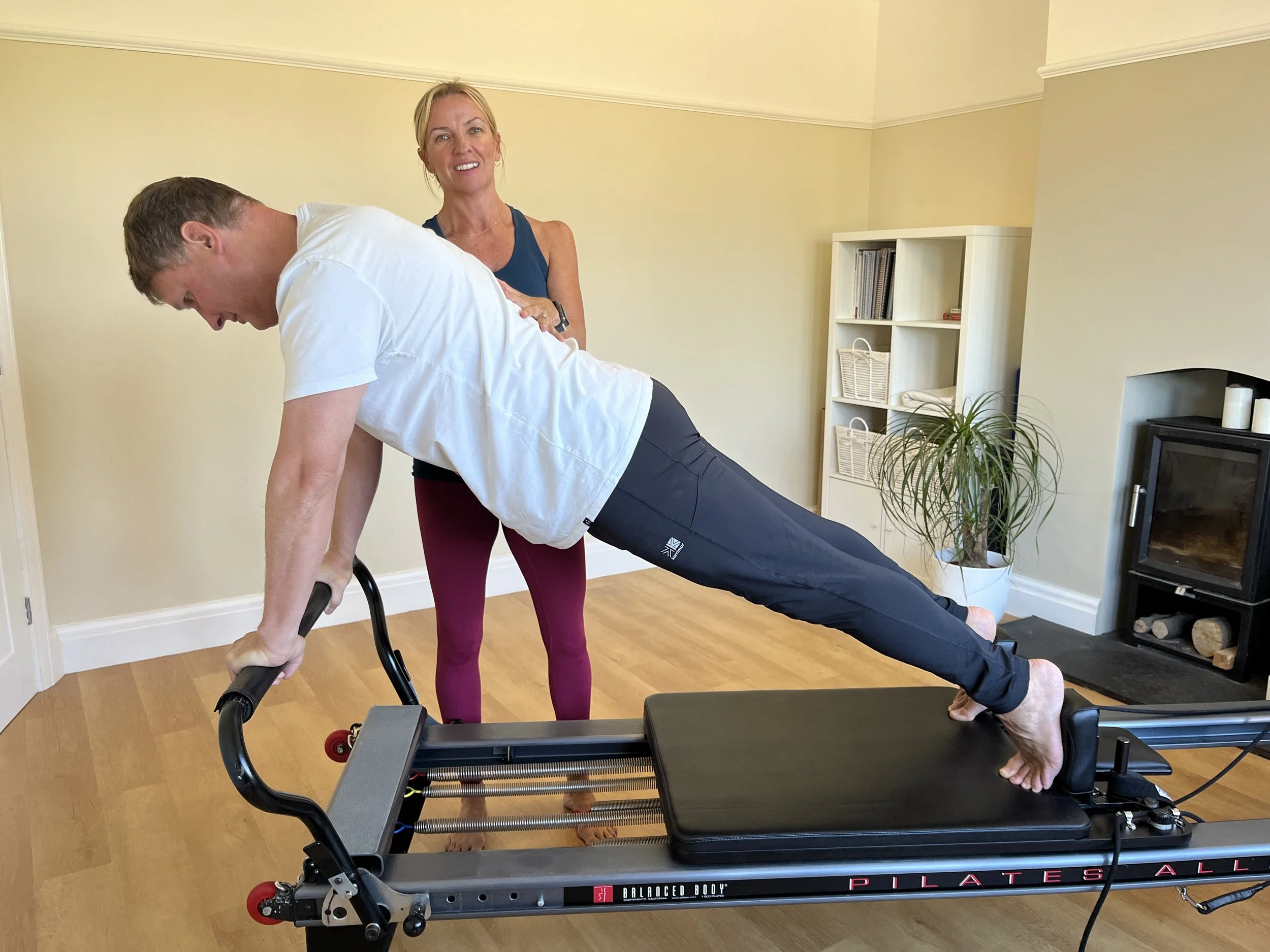 Louisa, founder at Move Well Studio helps a woman with alignment during a pilates class in Wetherby