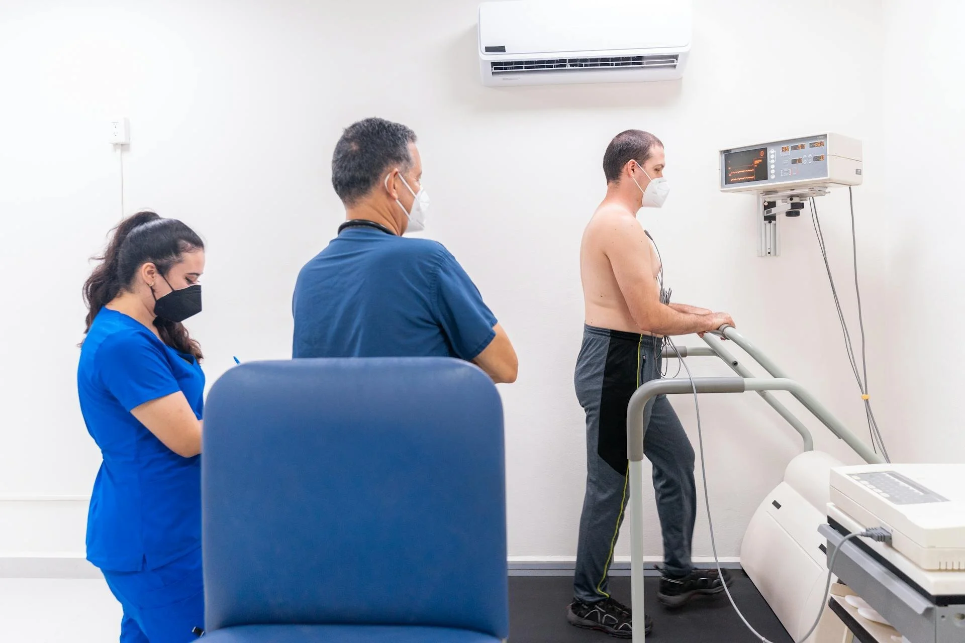 Two doctors supervising their patient who is on a running machine