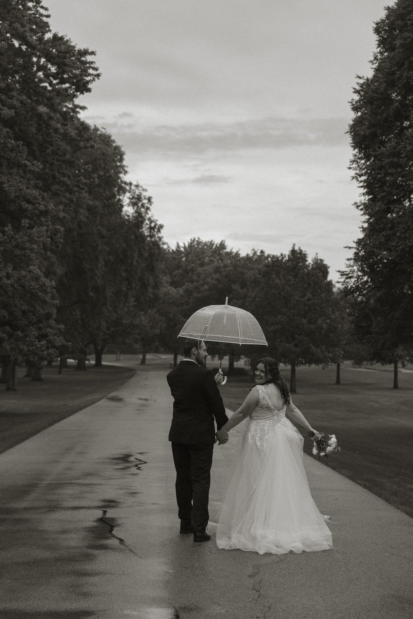 Bride and groom under clear umbrella in the rain, Aurora Country Club wedding