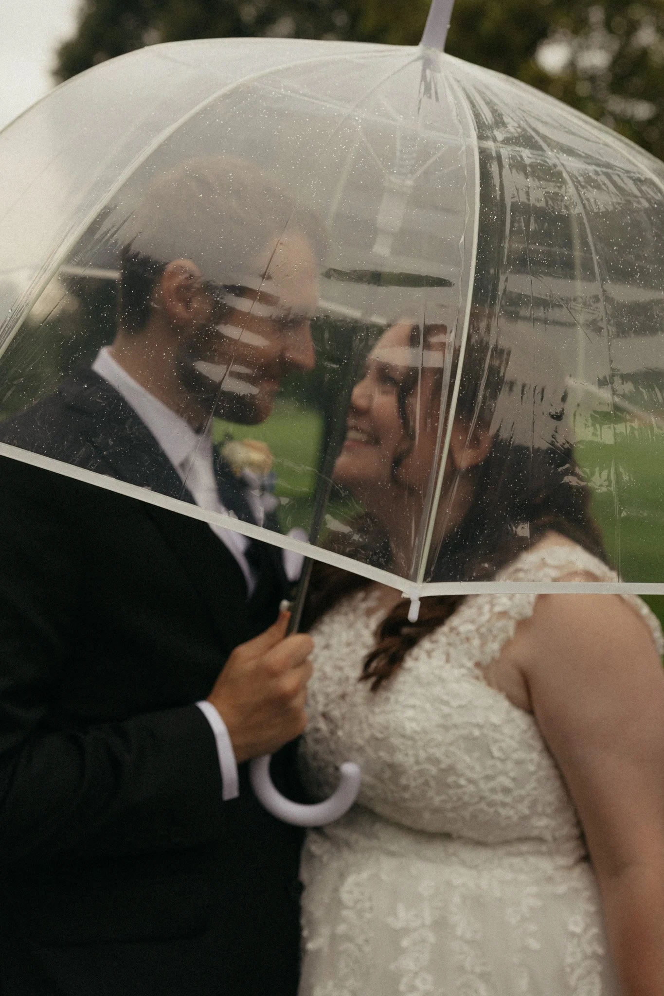 Bride and groom under clear umbrella in the rain, Aurora Country Club wedding