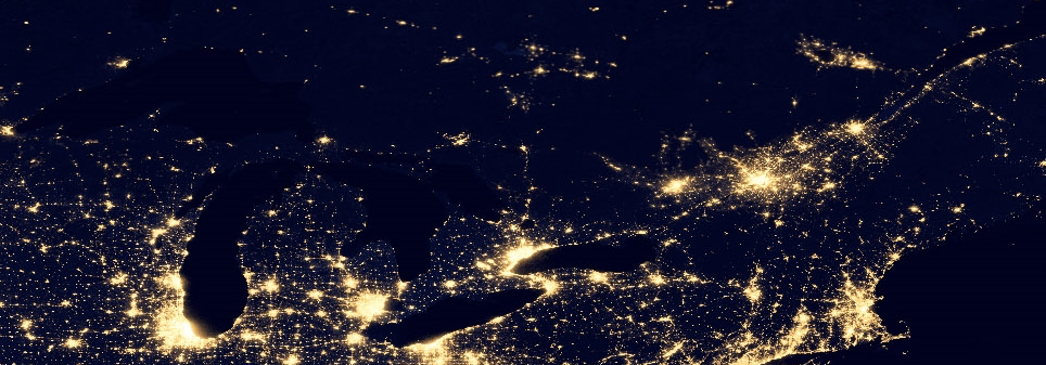 Nighttime satellite view of the eastern United States showing city lights, including the Great Lakes area and surrounding regions.