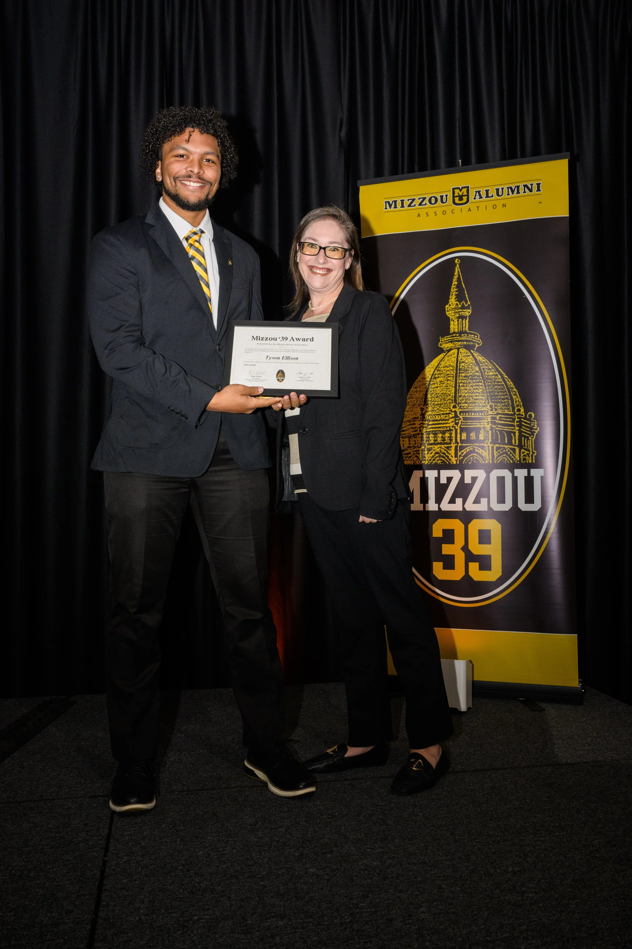 Tyson Ellison and his mentor, Amy Simons, accept the Mizzou '39 Award together on stage. The event is put on by the Mizzou Alumni Association.