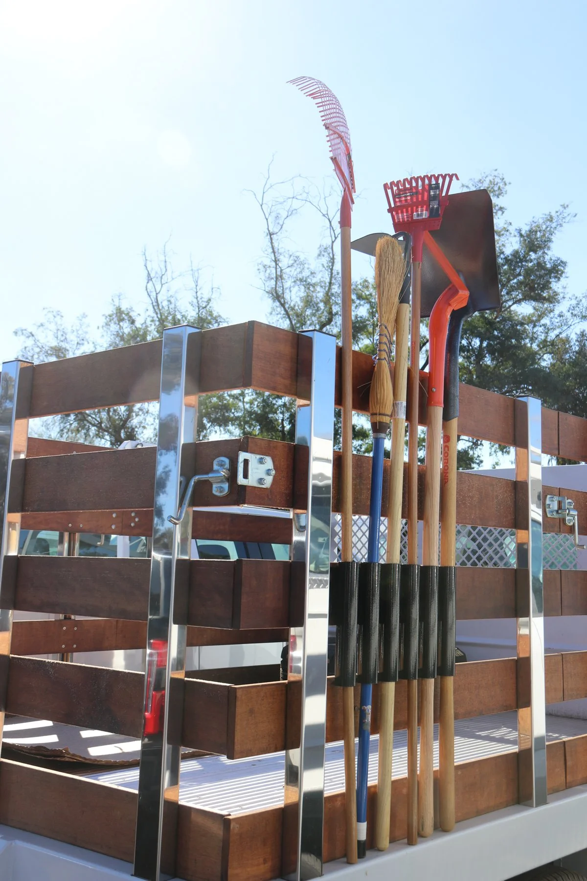 Image of Tool Tamer product - Open-tube Flush Mount version. Long-handled tools organized cleanly on the outside of a truck bed with slatted box.