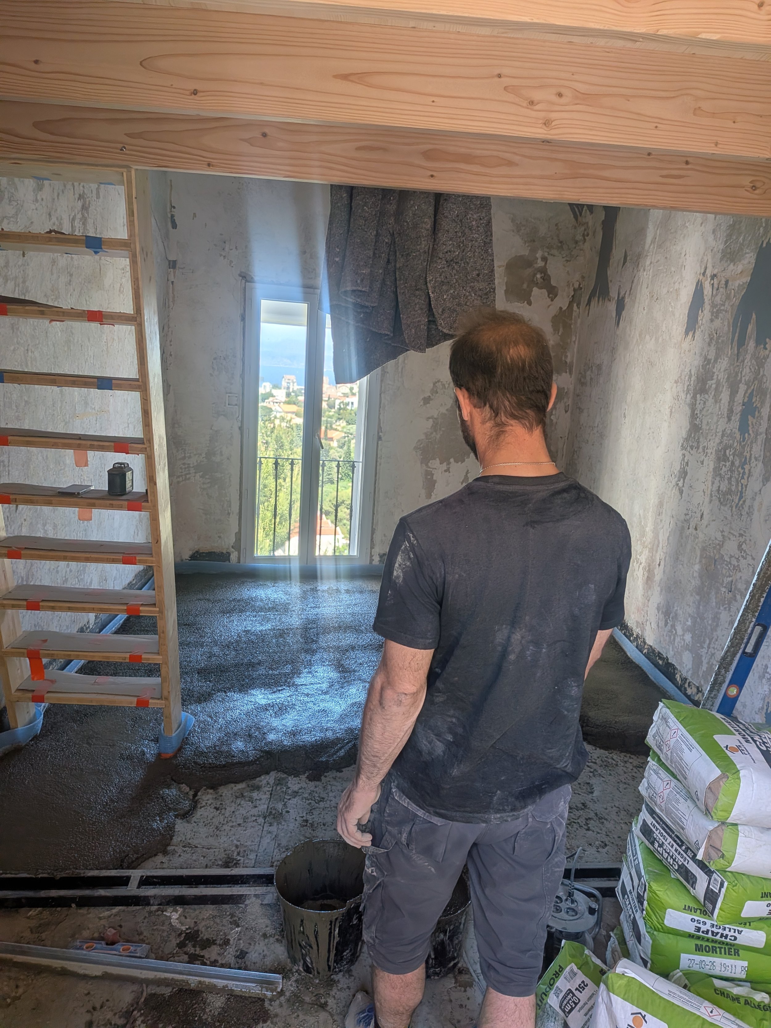 Ouvrier de Jeulin Habitat dans un appartement marseillais en cours de rénovation, murs mis à nu et escalier provisoire