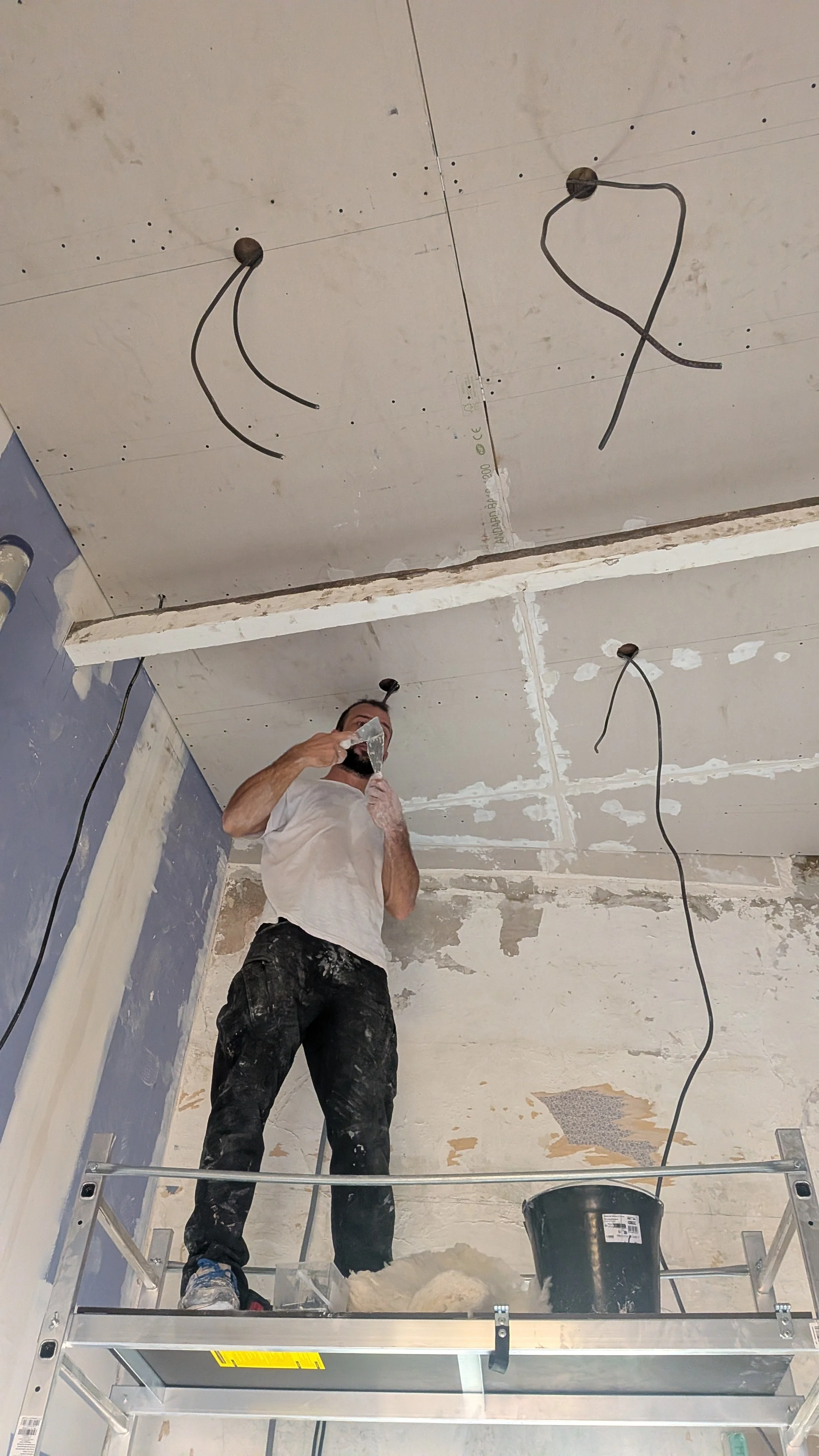 Ponçage et rebouchage d'un plafond avant peinture, avec masque de protection