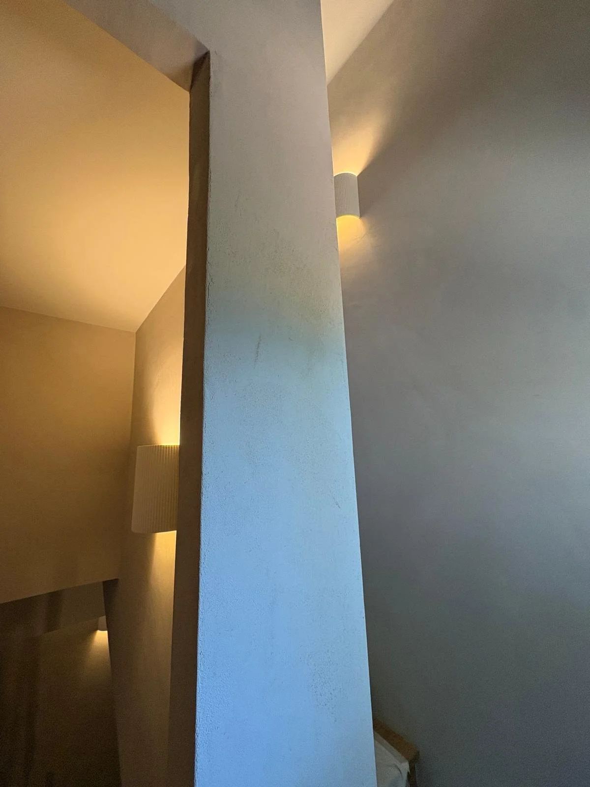 Mur en enduit à la chaux lissé, éclairé par une applique murale