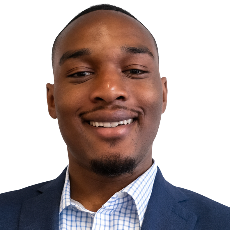 Close-up of a smiling Black man in a suit and checkered dress shirt, with a plain background.