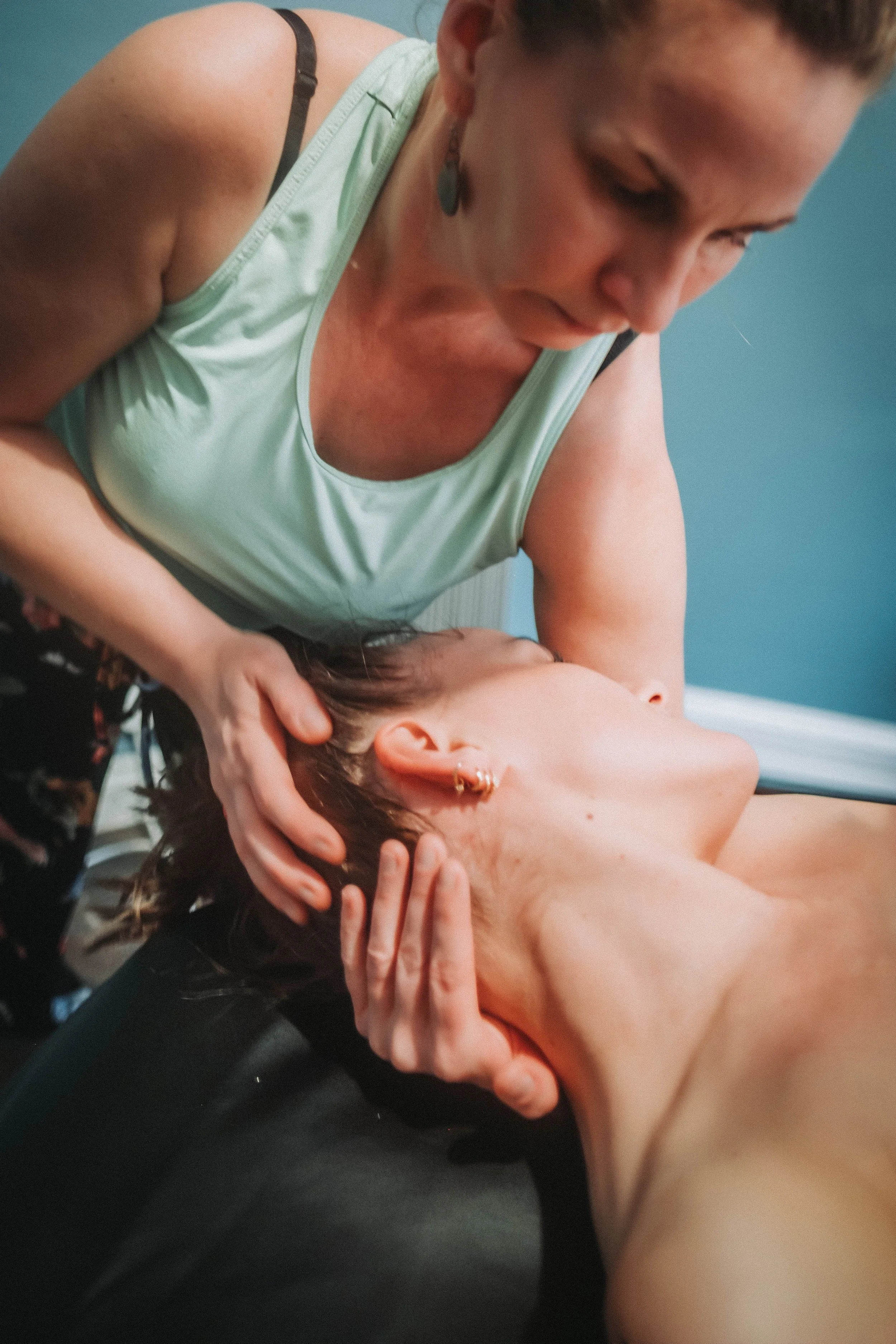 A woman receiving a massage from another woman in a room with blue walls.