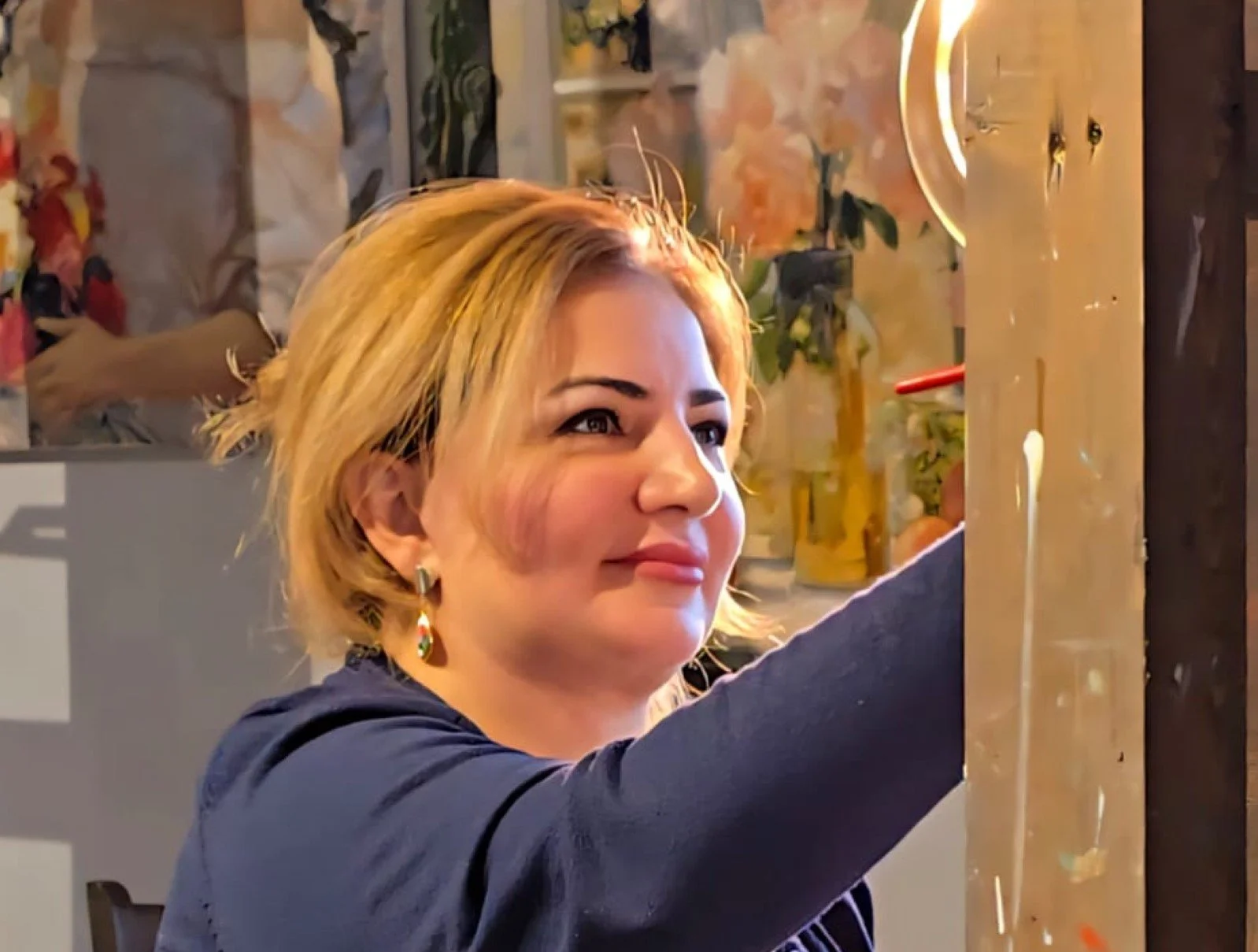 A woman painting on a canvas set on an easel in a colorful, decorated room.