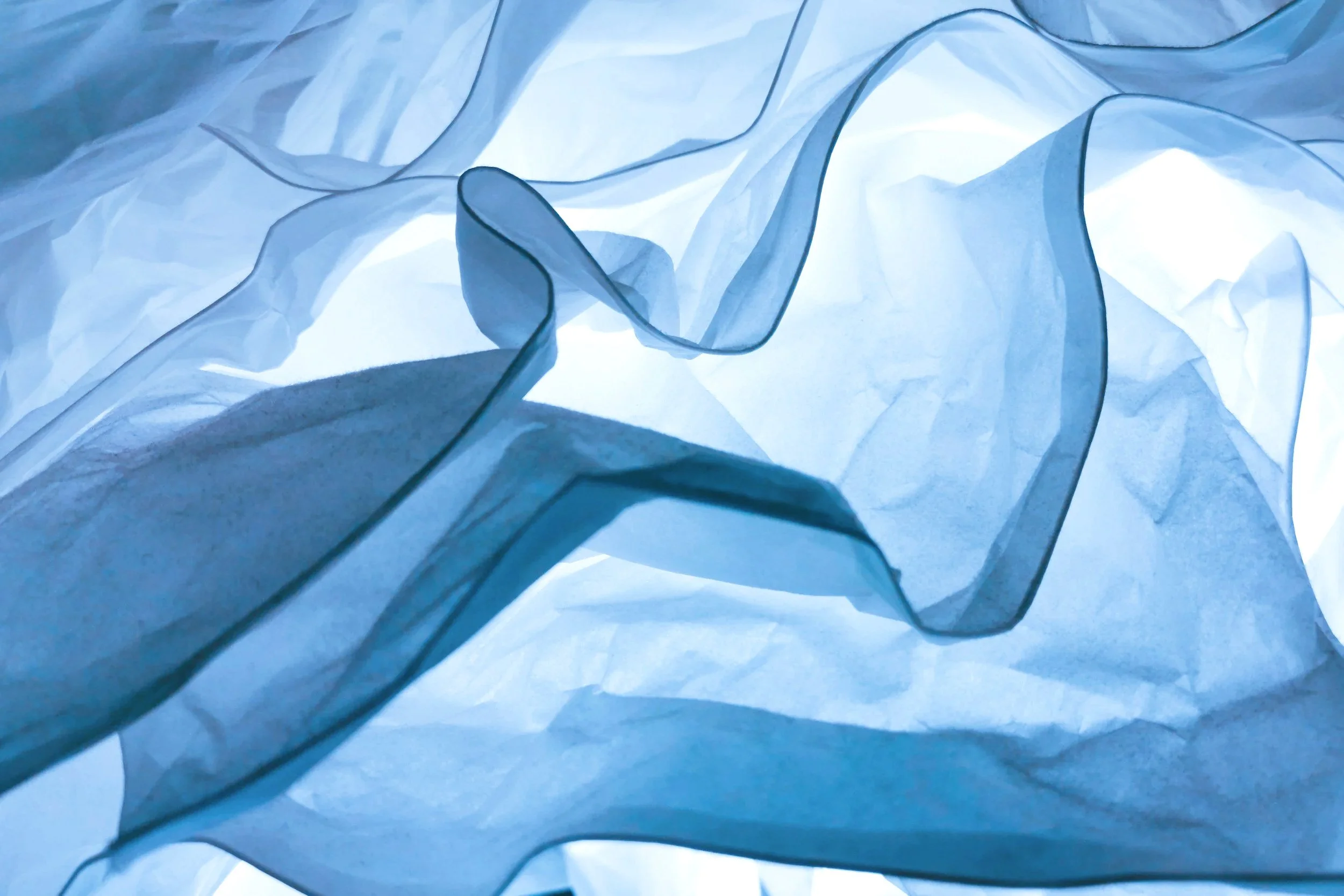 Blaues, transparentes, zerknülltes Papier in verschiedenen Tönen.
