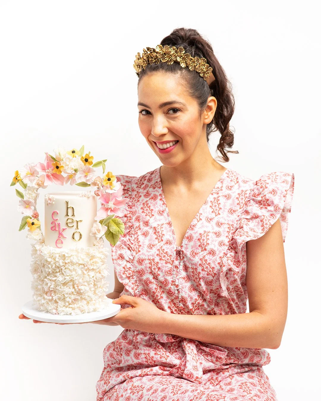 Portrait of Cake Hero artist Melissa Torres, holding a custom cake with sugar flowers