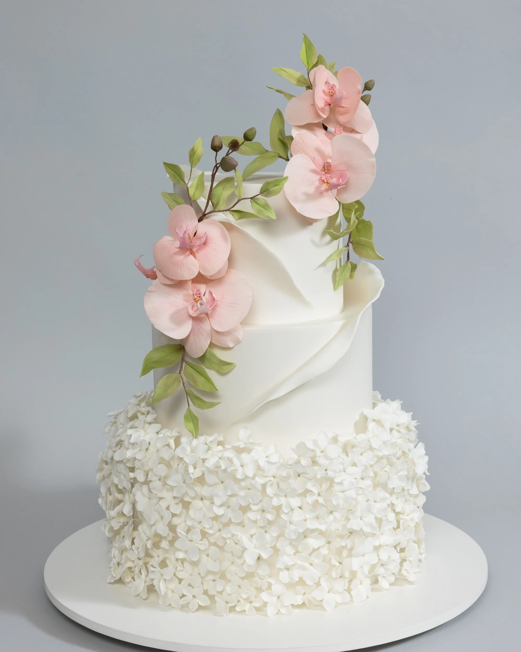 Romantic white cake covered in white flowers and Pink Orchids