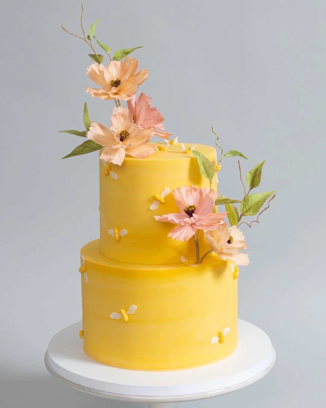 Yellow spring cake with bumblebees and pink cosmos