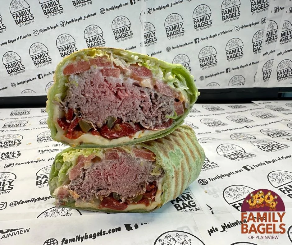 Cross-section of a grilled wrap containing ground beef, lettuce, tomato, and other vegetables, with a branded paper background from Family Bagels.