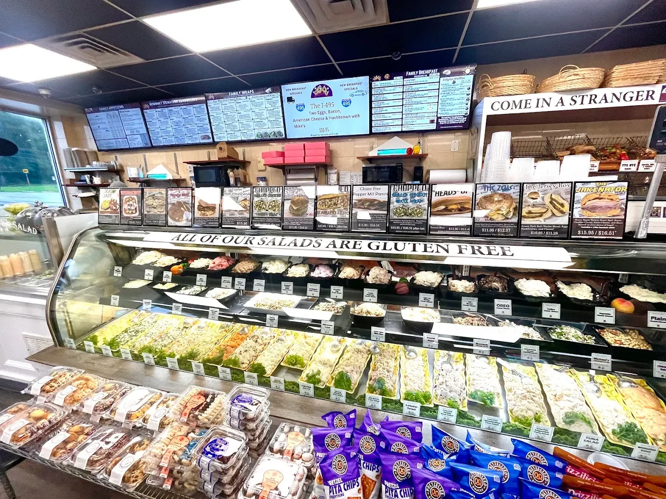 Deli display case with salads and packaged snacks at a grocery store or sandwich shop.