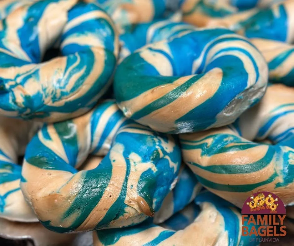 Close-up of bagels with swirl pattern of blue, beige, and white, branded with a Family Bagels logo.