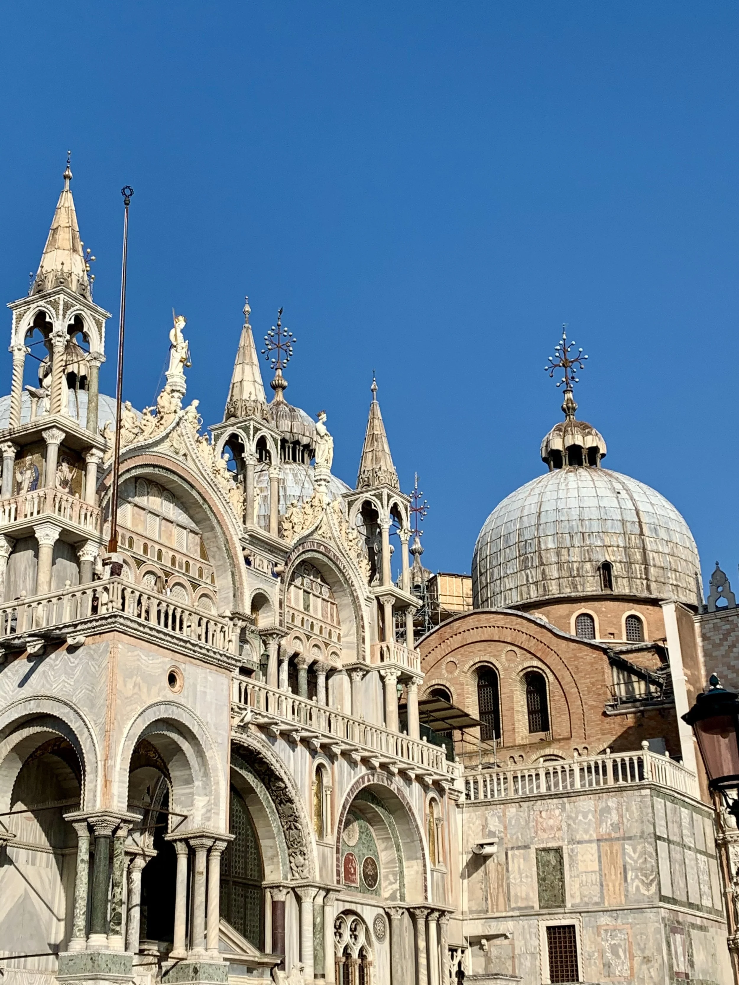 The facade of a historic ornate cathedral with multiple spires, detailed carvings, and large arched windows, set against a clear blue sky.