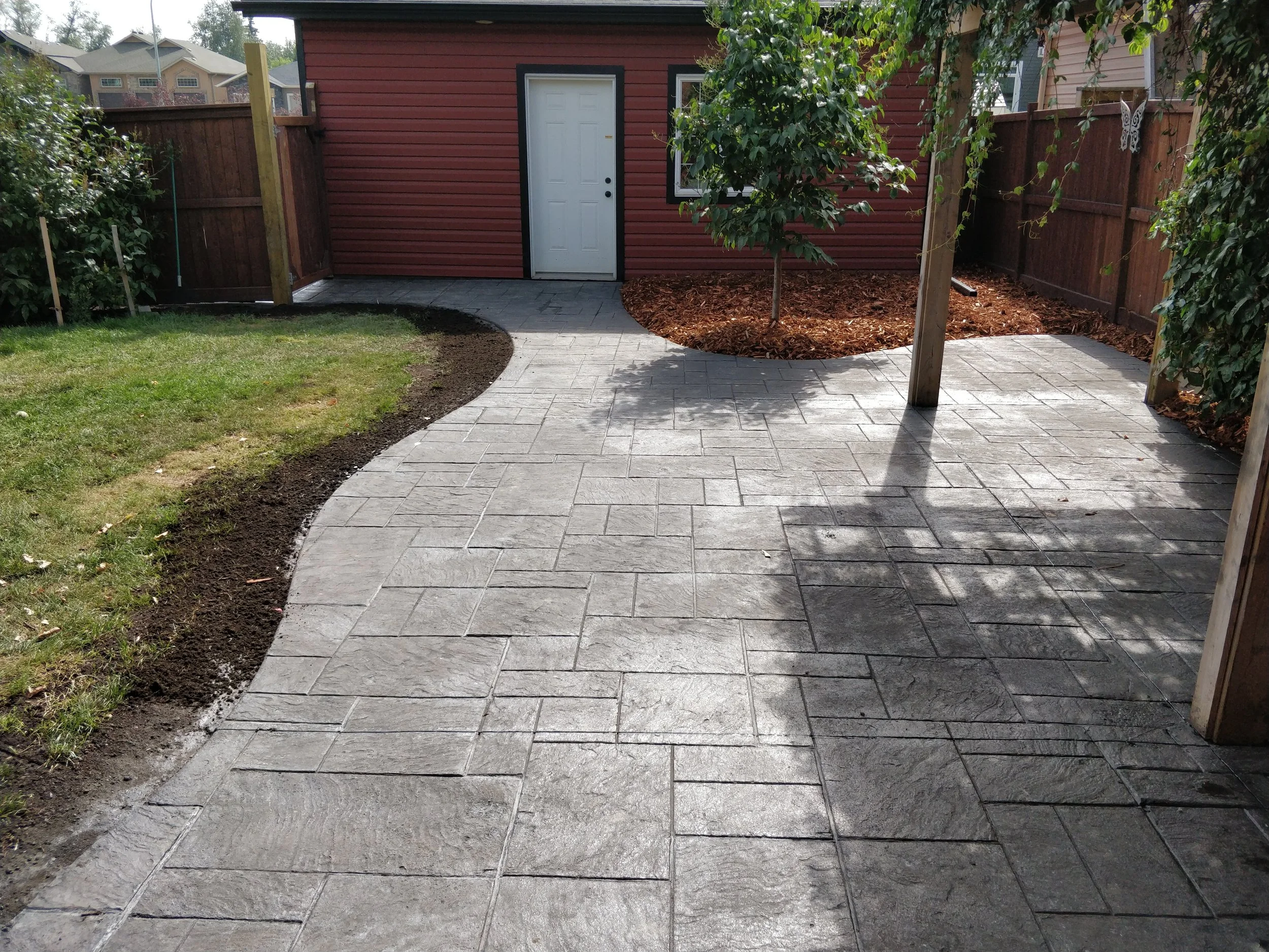 Stamped concrete patio leading to a garage man door with a stamped concrete walkway connecting both together