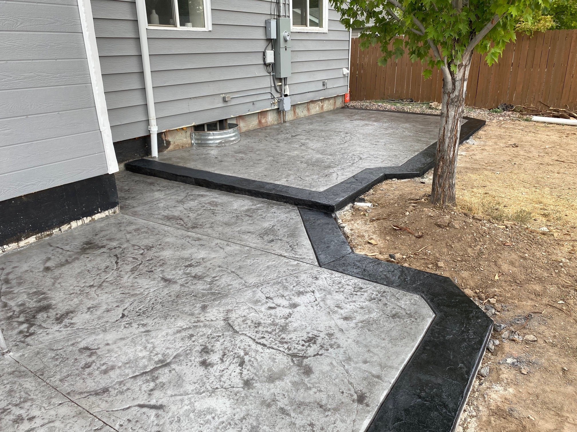 Stamped concrete patio with dark black border in a tiered design.