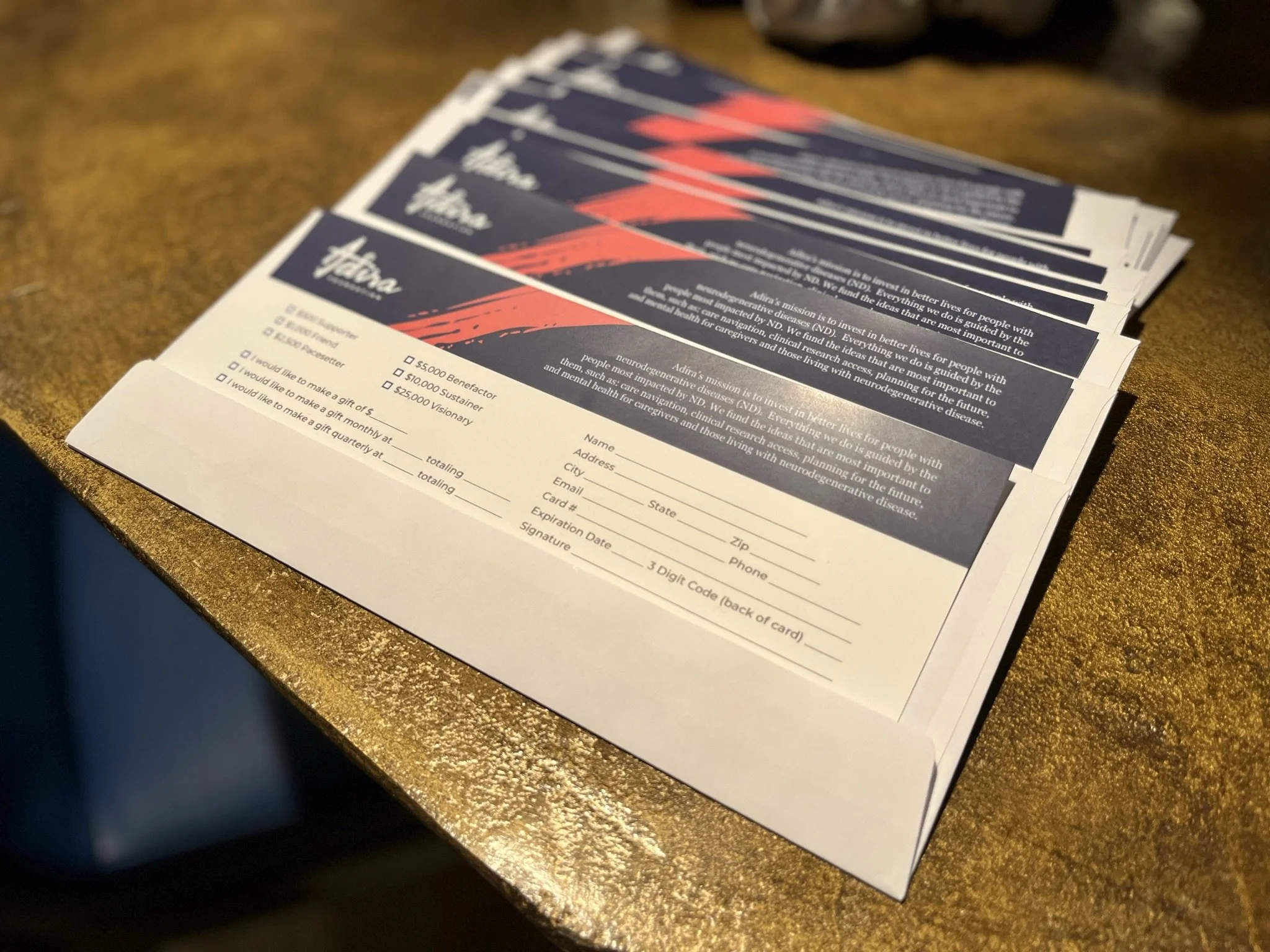 Stack of informational flyers with a blue and red abstract design on a wooden surface.