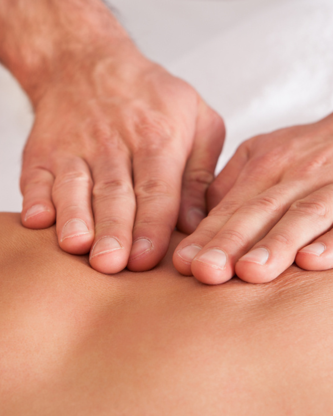 Close-up of a massage therapist's hands applying pressure to a person's back during a massage.