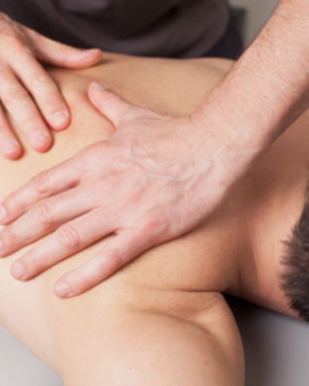 A close-up of a person receiving a massage on their back from a massage therapist.