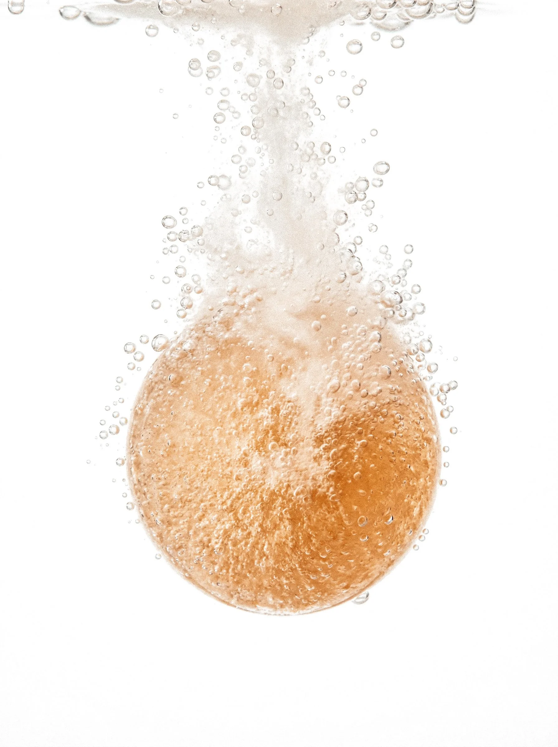 Close-up of a brown egg submerged in sparkling water with bubbles surrounding it.