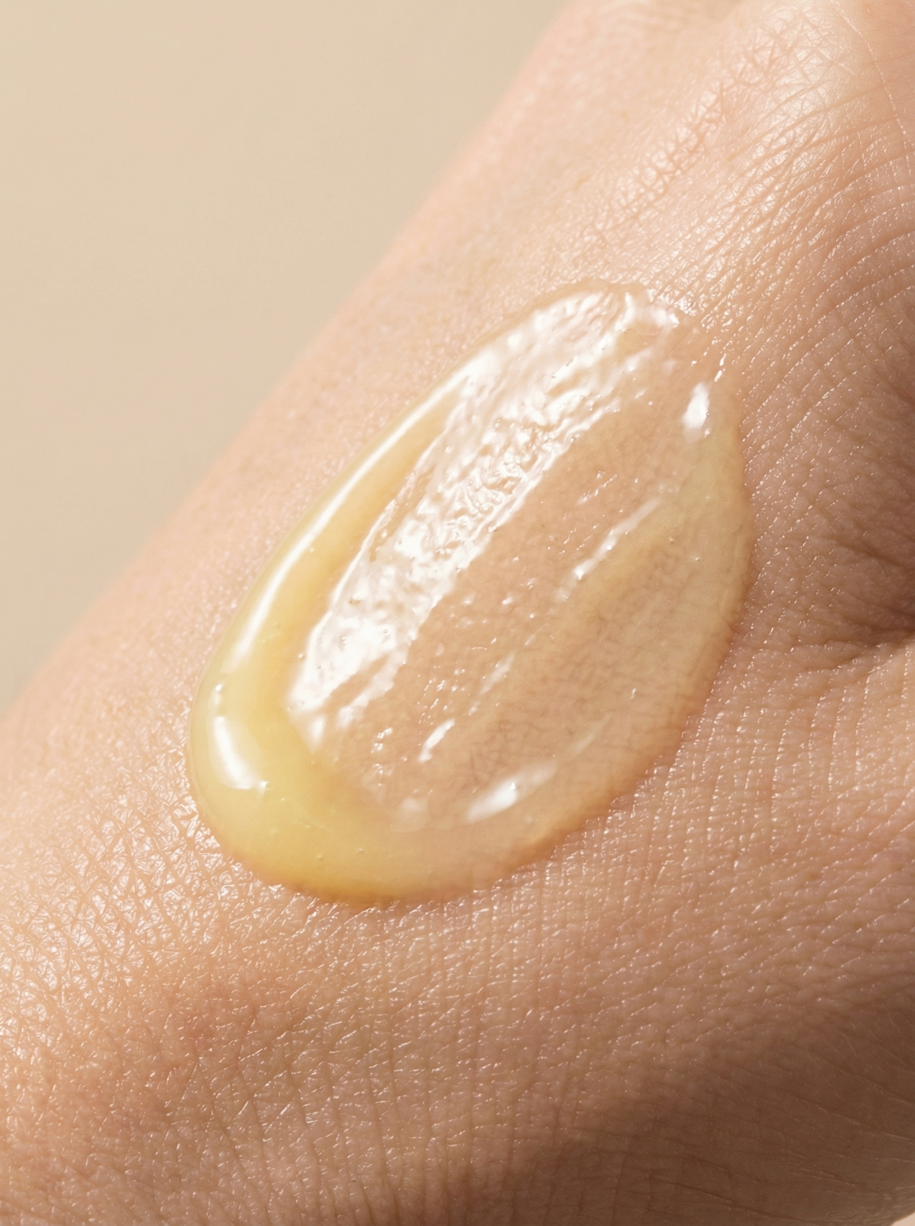 Close-up of a finger with a small amount of clear, glossy liquid or gel on the fingertip.