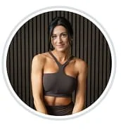 Woman in athletic attire standing against a dark, striped background.