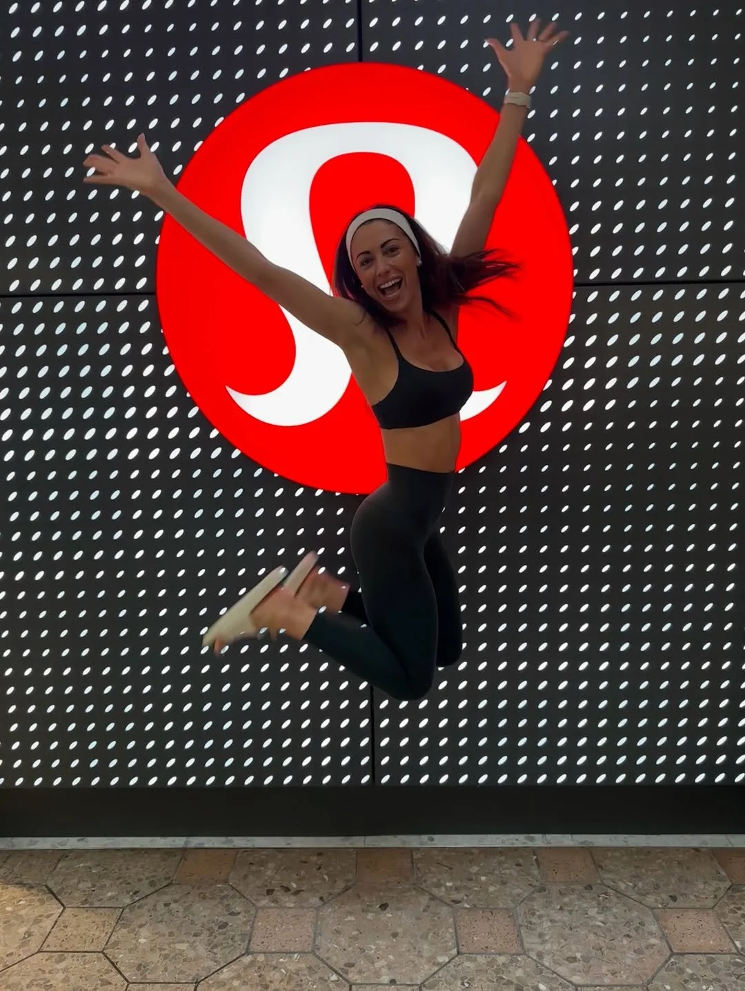 Woman jumping excitedly in front of a large red and white target logo at an indoor location.