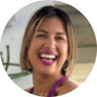 A woman with short hair smiling and laughing in an indoor setting.