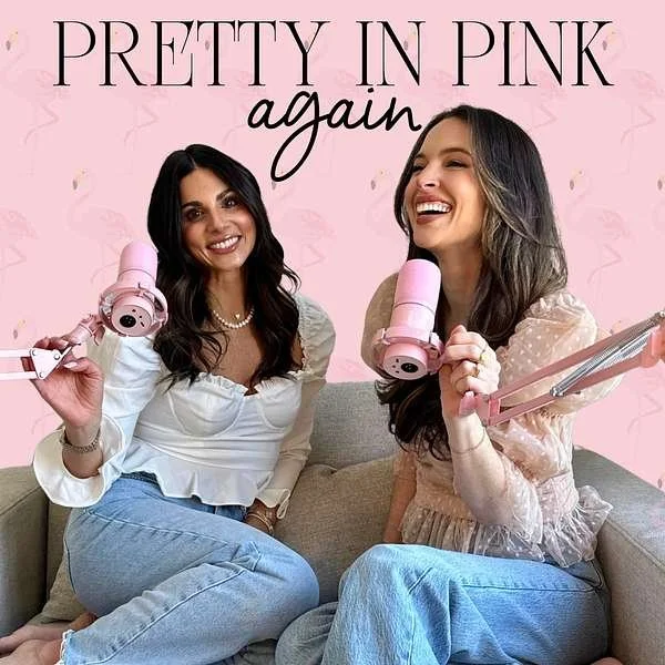 Two women sitting on a gray couch, each holding pink gaming microphones, smiling and enjoying themselves. The background is pink with the text 'PRETTY IN PINK again' at the top.