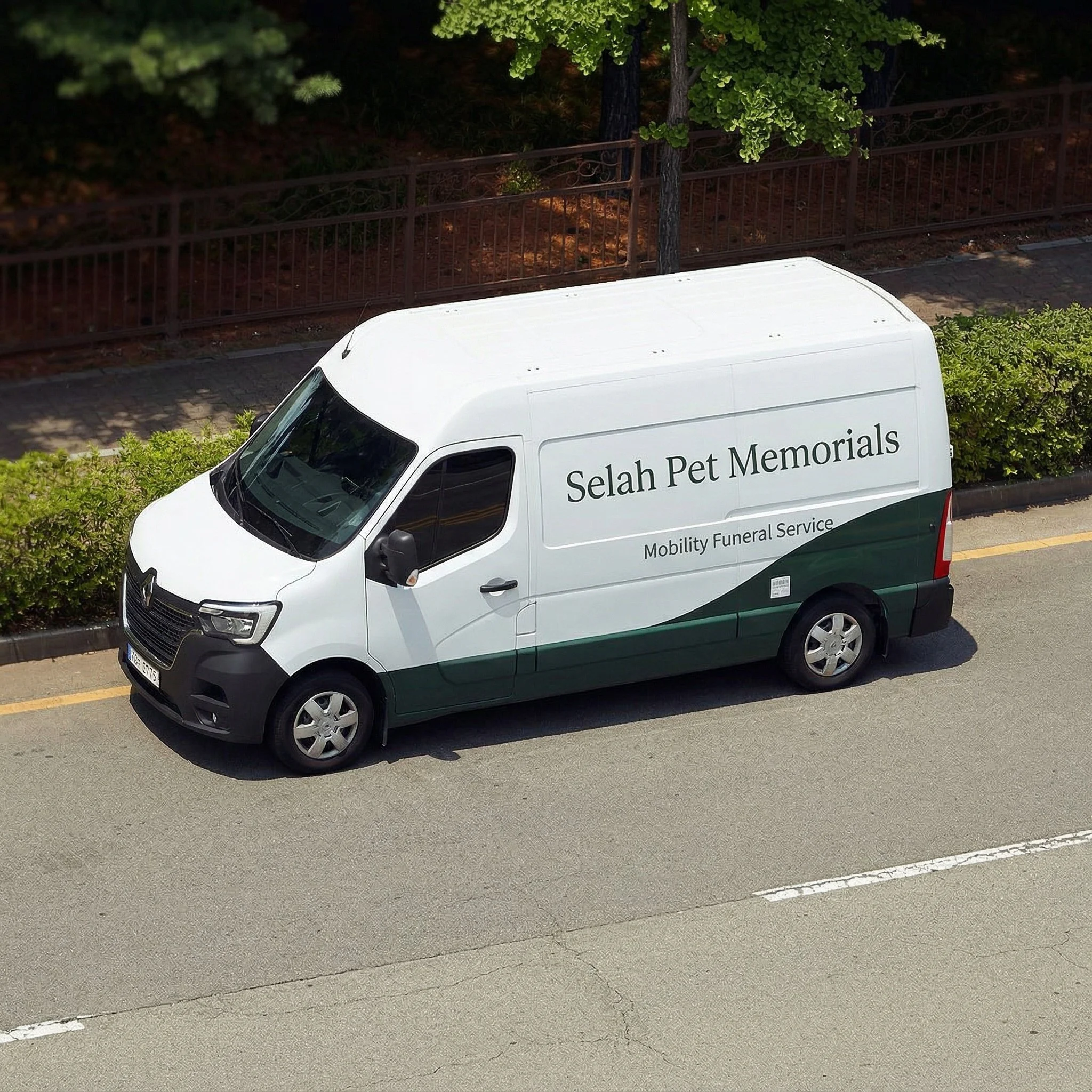 White and green van labeled 'Selah Pet Memorials' and 'Mobility Funeral Service' parked on the side of a street, with trees and bushes in the background. White glove service pet transportation in NYC.