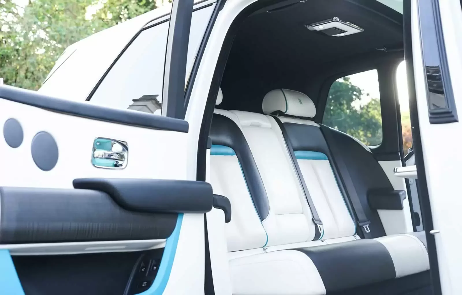 The interior of a modern electric vehicle showing the front and rear seats with black and white upholstery and a large window.