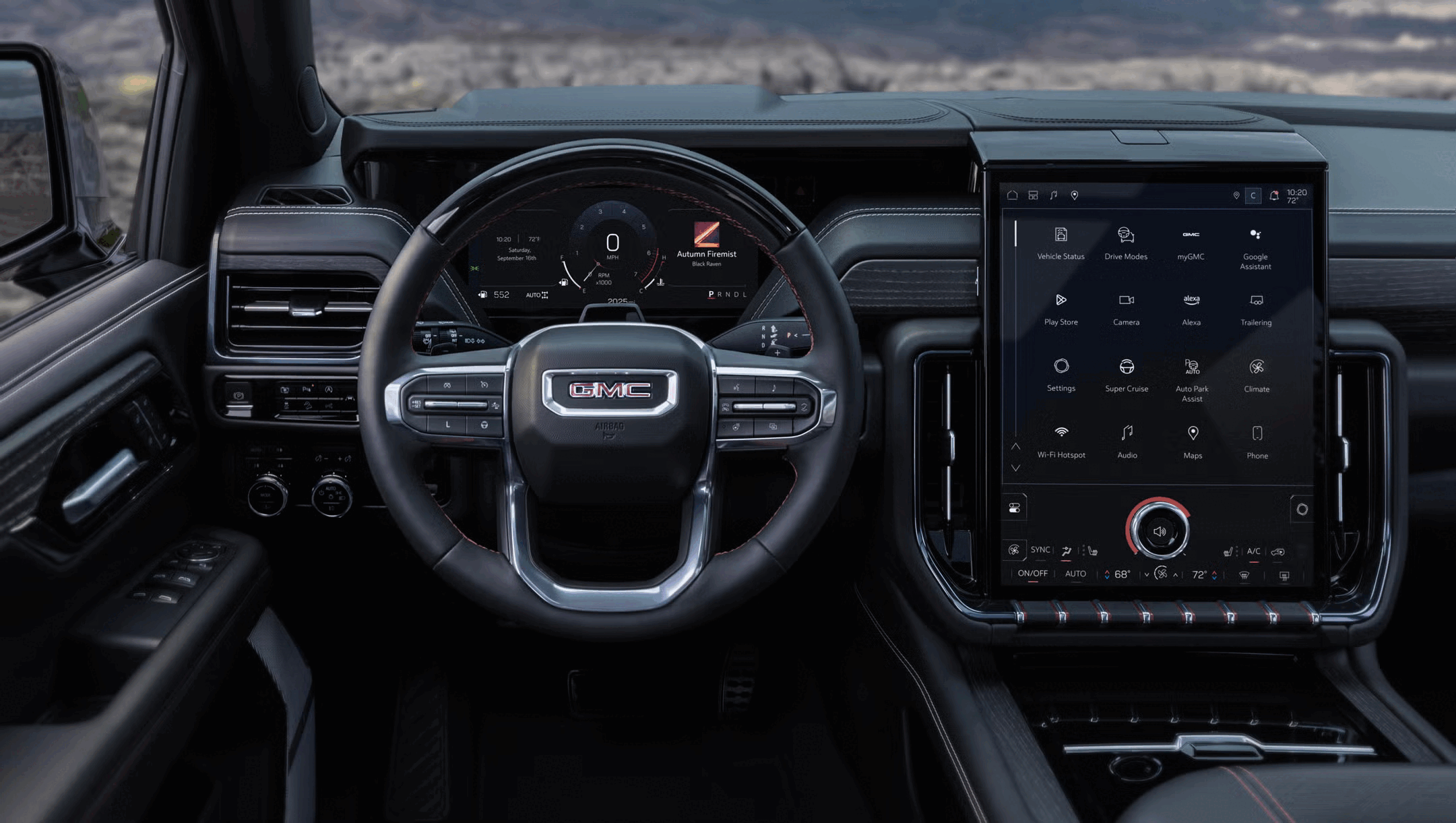 Interior of a GMC vehicle dashboard showing a digital instrument cluster, a large touchscreen display with vehicle controls and apps, including vehicle status, drive modes, Google Assistant, and climate control, with a view of a rocky landscape outsi