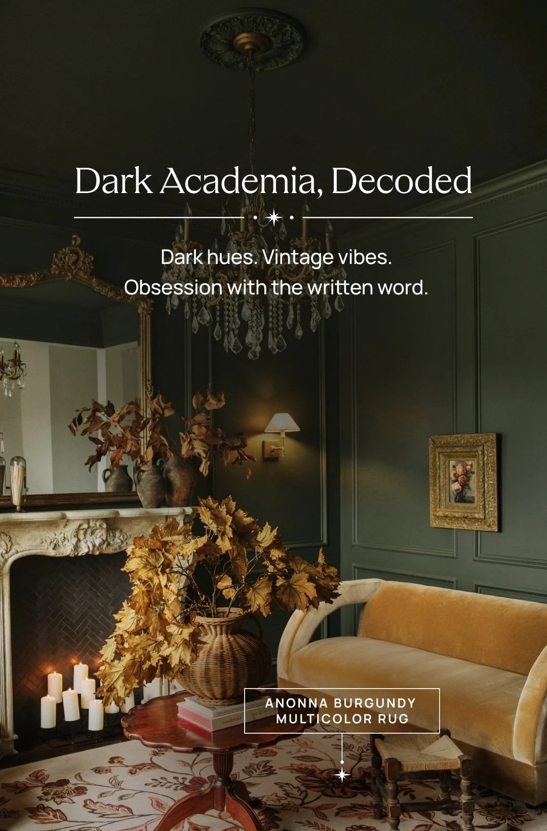 A vintage living room with dark green walls, a chandelier, a mirror above a fireplace with candles, a yellow velvet sofa, a round wooden table with a basket of dried leaves, a framed floral painting, and warm lighting.