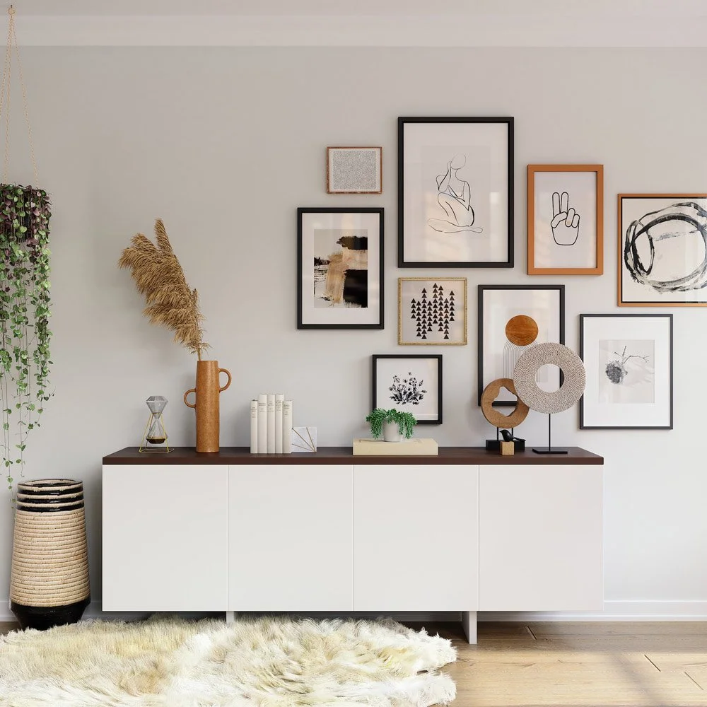 Modern living room decor featuring a white sideboard with various vases, books, and art pieces on top, a gallery wall with framed minimalist artwork and photos, a woven basket, a hanging plant, and a fluffy rug.