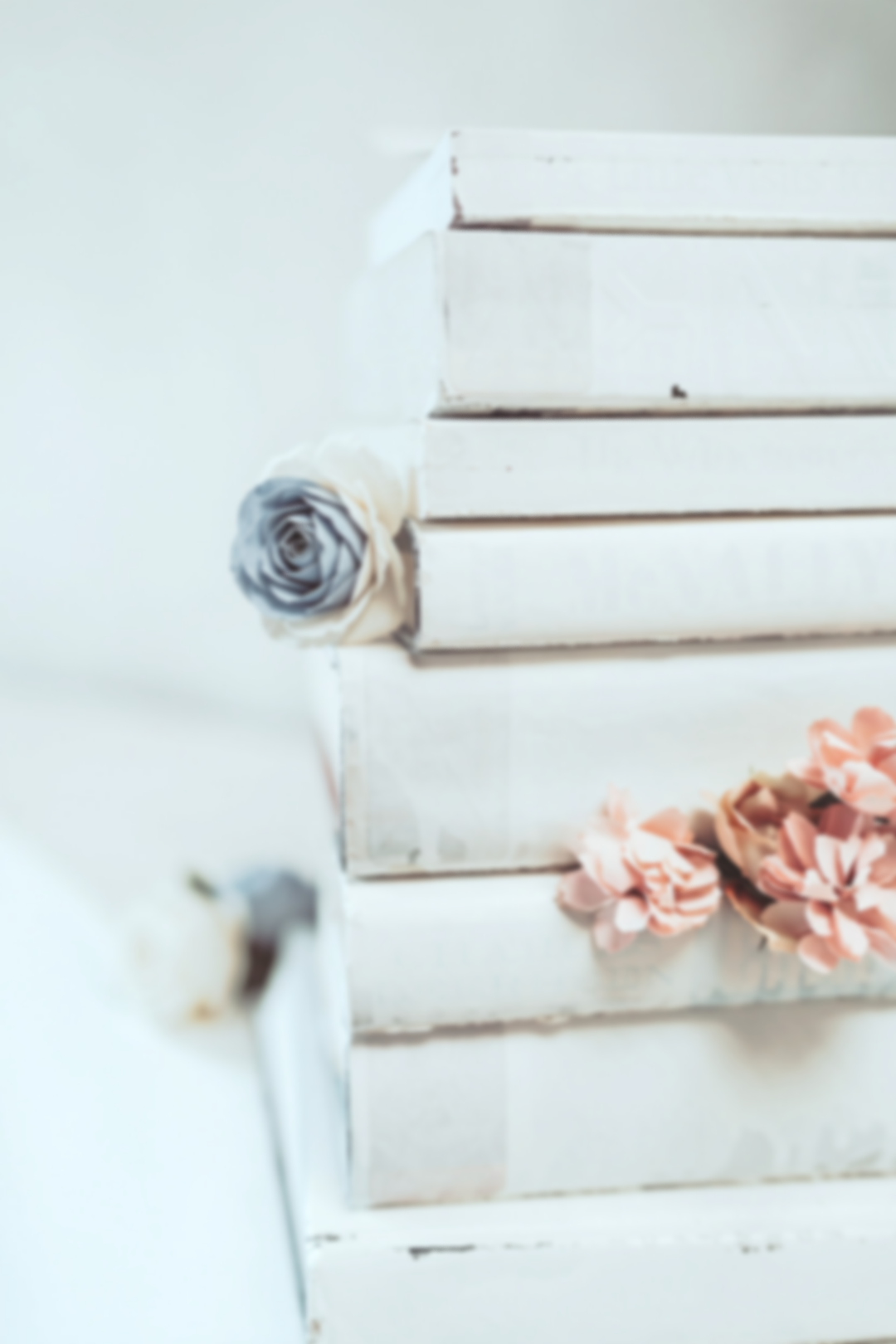 Stack of white gift boxes decorated with pastel-colored flowers, including a grey and white rose and peach blossoms, on a white surface.