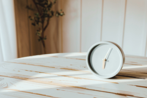 A round clock lying on its side on a white wooden table.