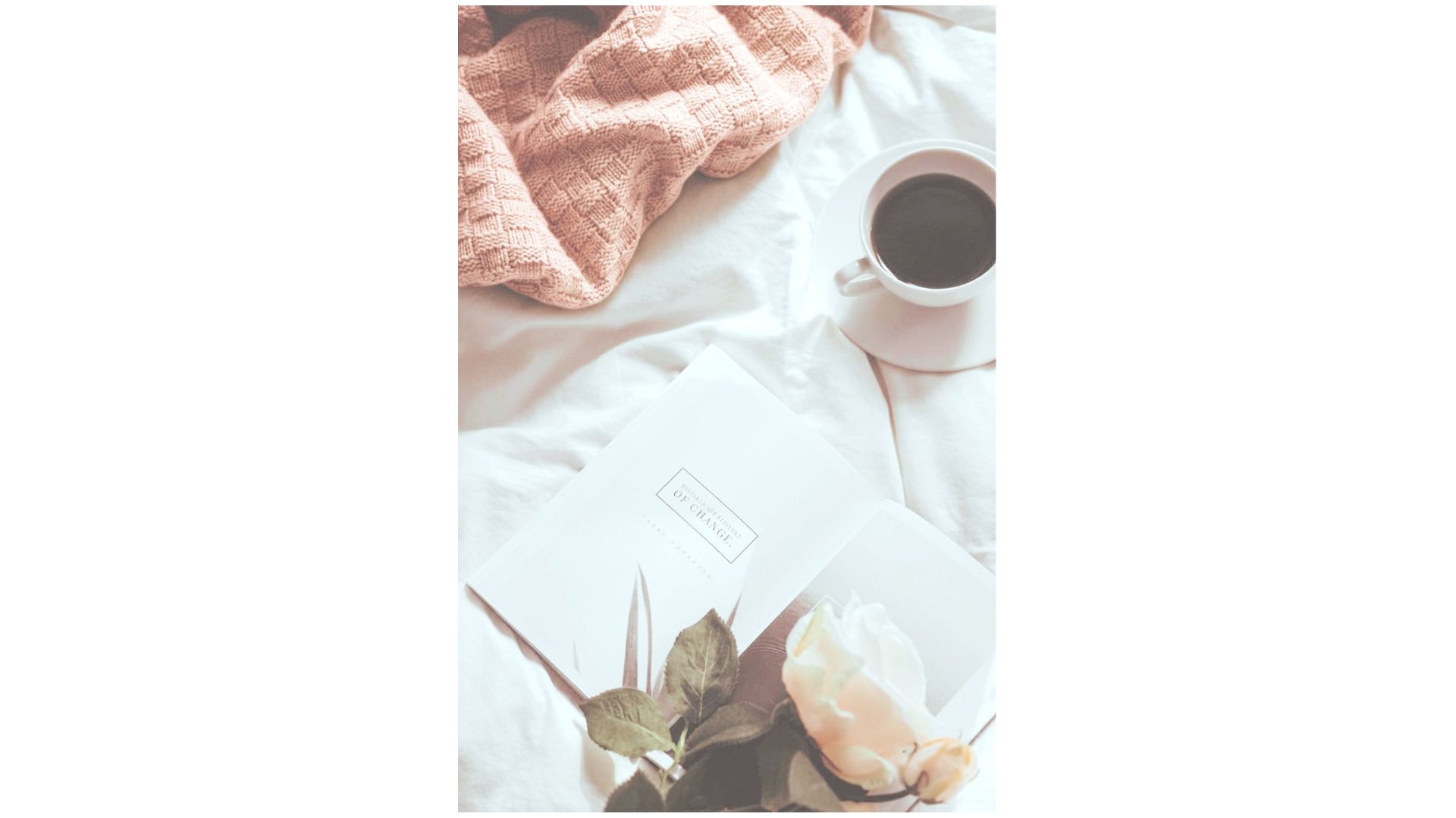 A cozy scene on a bed with a pink knitted blanket, an open book titled 'Introduction to Oenology,' a cup of black coffee on a saucer, and a white rose in the foreground.