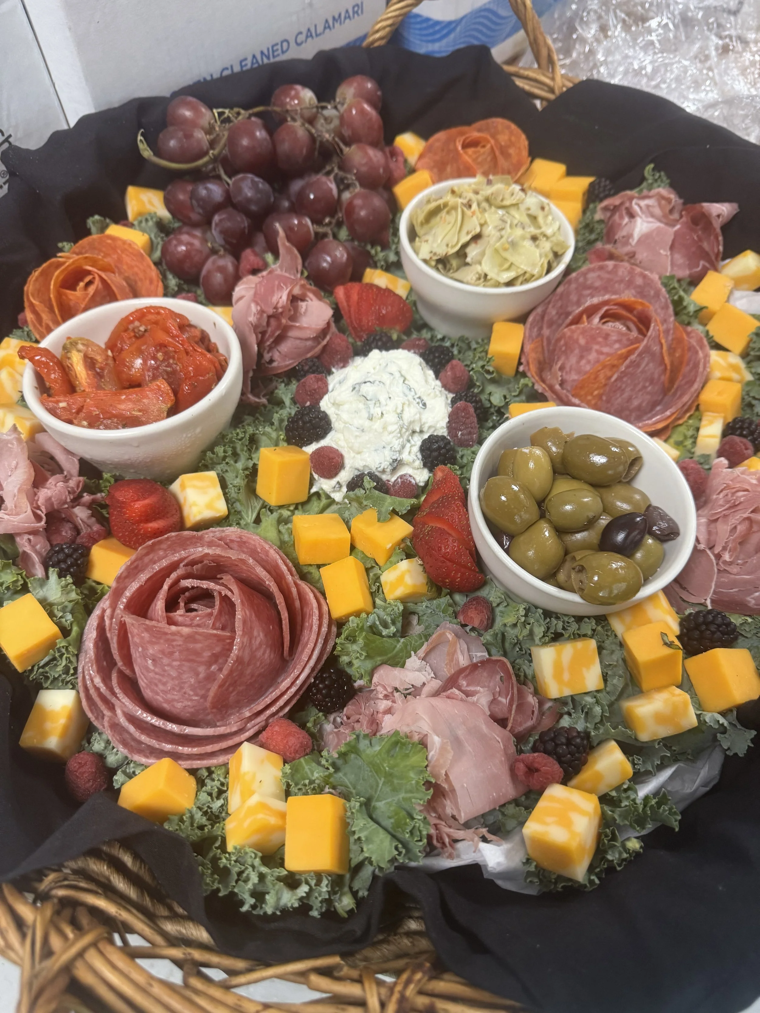 Charcuterie board with grapes, cheeses, meats, strawberries, blackberries, raspberries, olives, artichoke dip, and roasted red peppers.