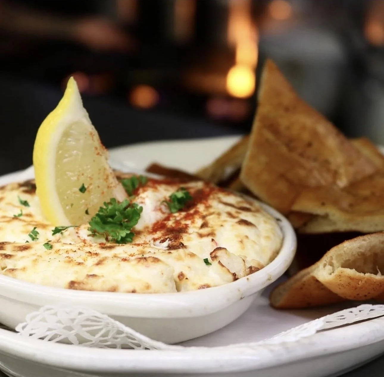 Baked dish topped with herbs and lemon wedge, served with toasted bread.