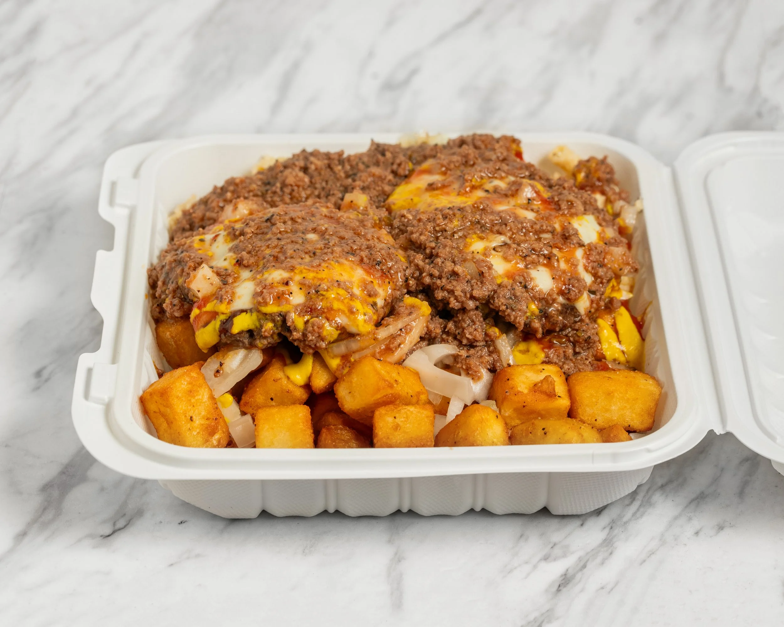 A takeout container filled with a meal of seasoned ground beef, melted cheese, diced onions, and crispy cubed potatoes on a marble surface