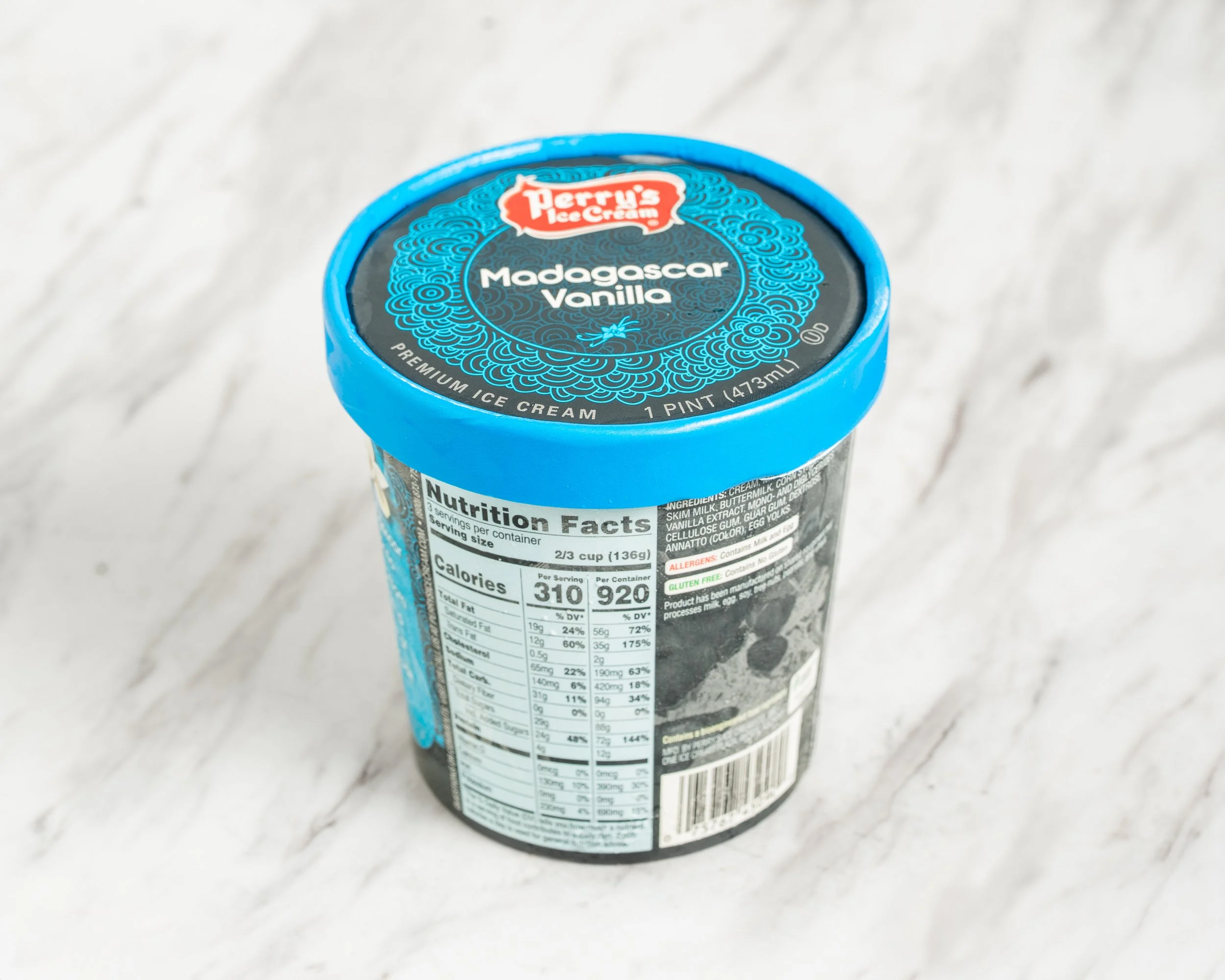 A pint container of Perry's Ice Cream Madagascar Vanilla flavor on a light-colored marble surface.