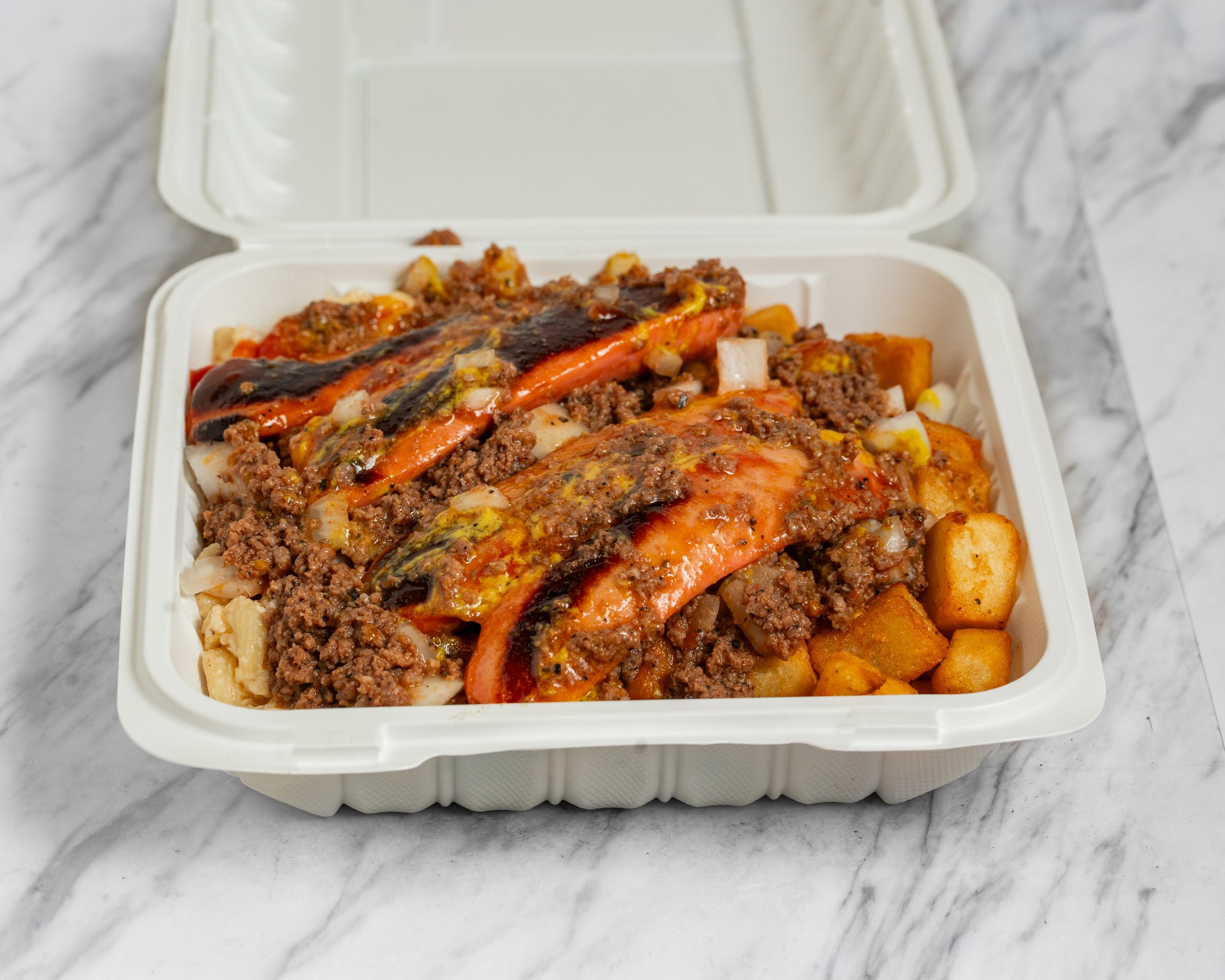 Takeout container filled with chopped beef, roasted red peppers, and diced onions on top of roasted potatoes.