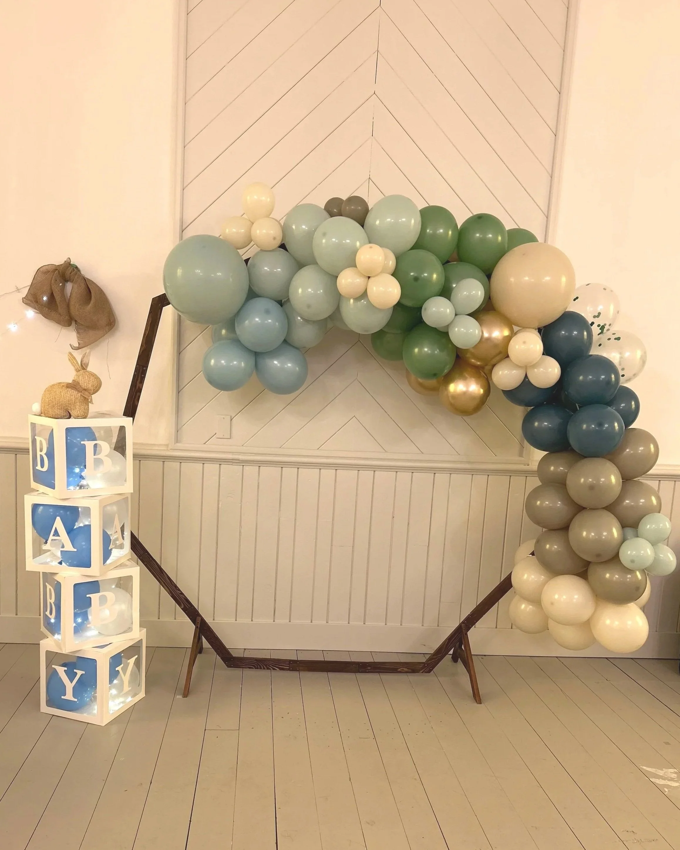balloon arch with blue and green balloons, stacked boxes that spell baby