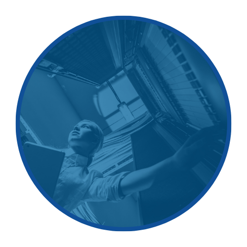 A person working inside a data center or server room, reaching towards server racks.