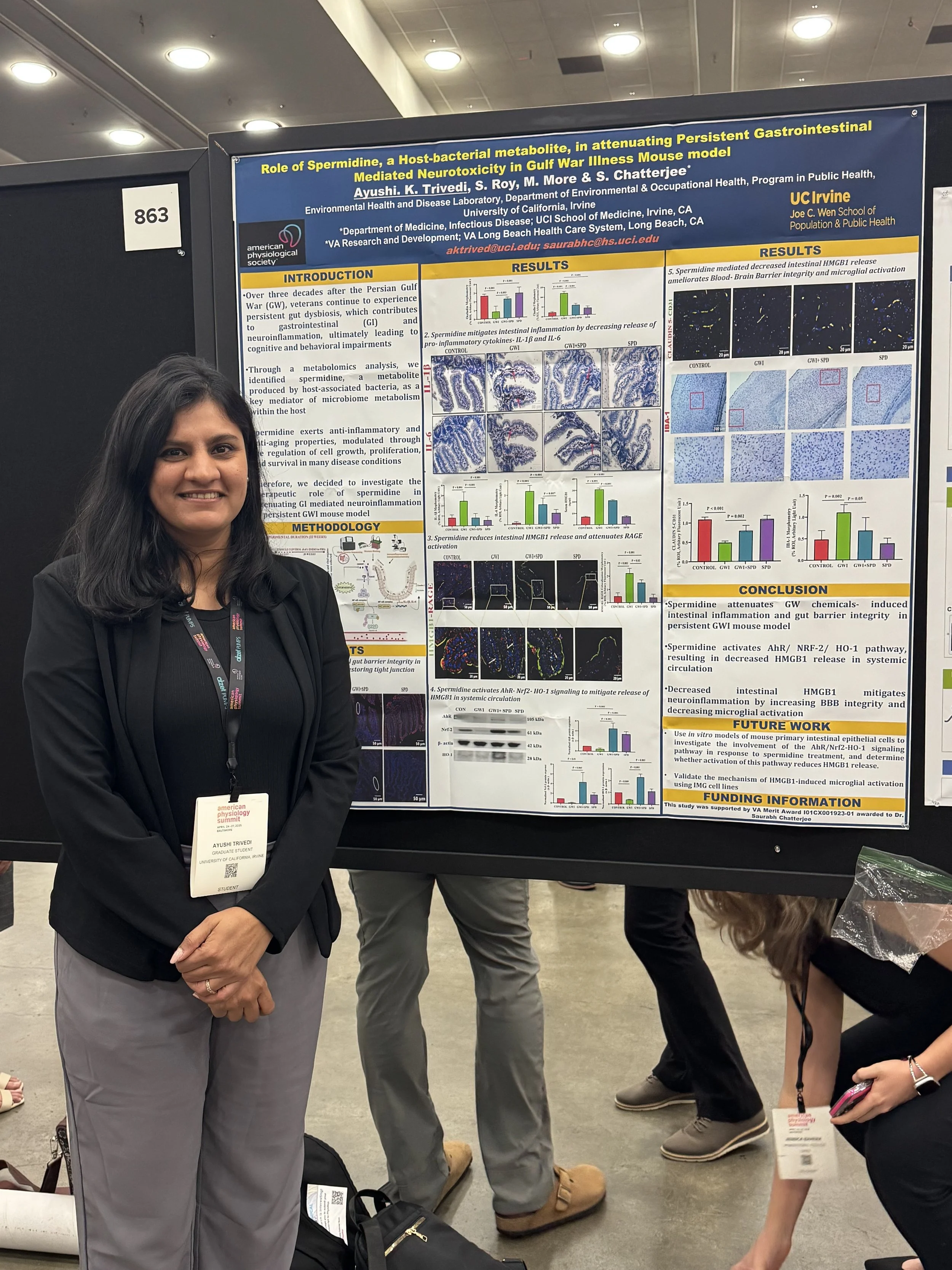 A woman standing next to a scientific research poster at a conference. The poster discusses the role of spermidine in attenuating gastrointestinal inflammation and gut barrier integrity in a Gulf War Illness mouse model.