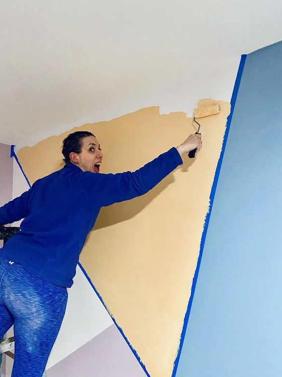 Sarah painting color block mural of yellow and blue